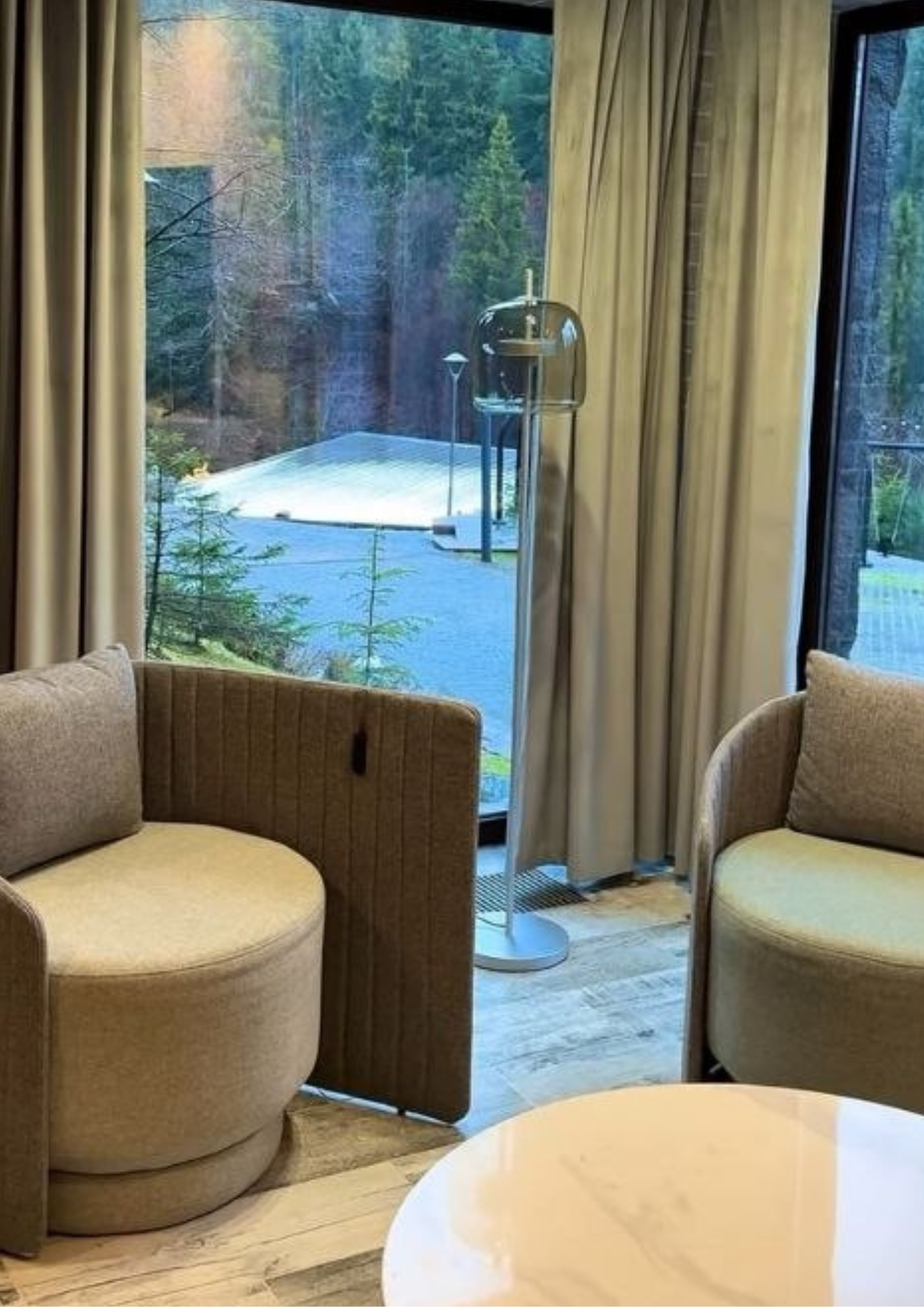 Lounge seating with floor-to-ceiling windows opening onto the forest